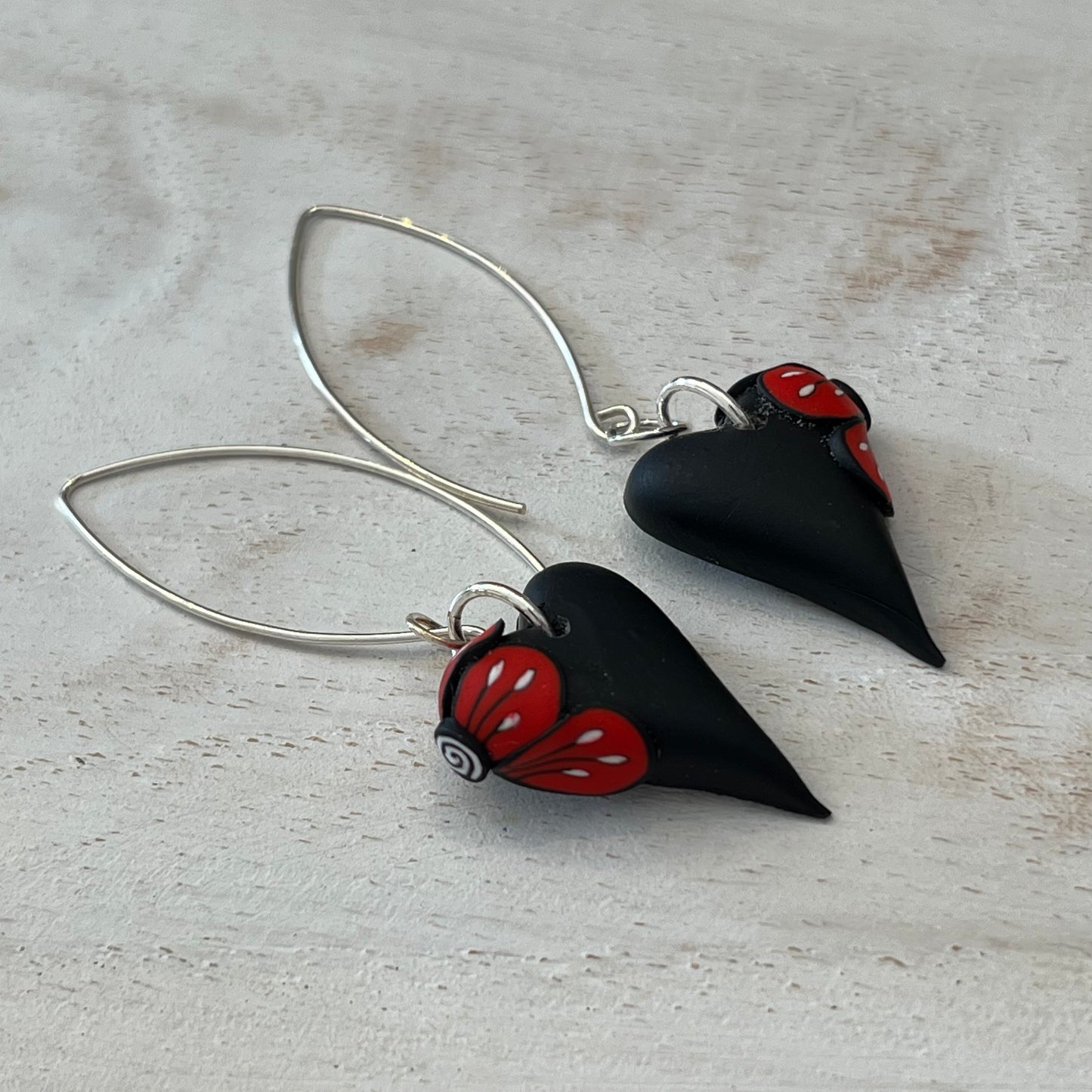 Handcrafted black heart-shaped earrings with red flower detail by Lanzarote artisan Stephanie Fraselle, paired with matching pendant (sold separately)