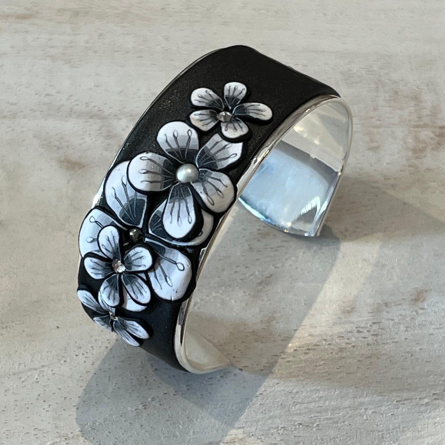 Moonlit Shimmer Blossom Cuff by Stephanie Fraselle featuring polymer clay florals and Swarovski crystals, handcrafted in Lanzarote
