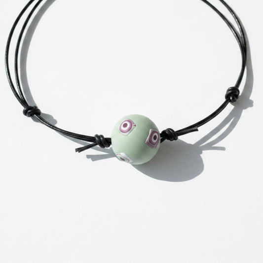 Necklace with a green bead on a light wooden surface