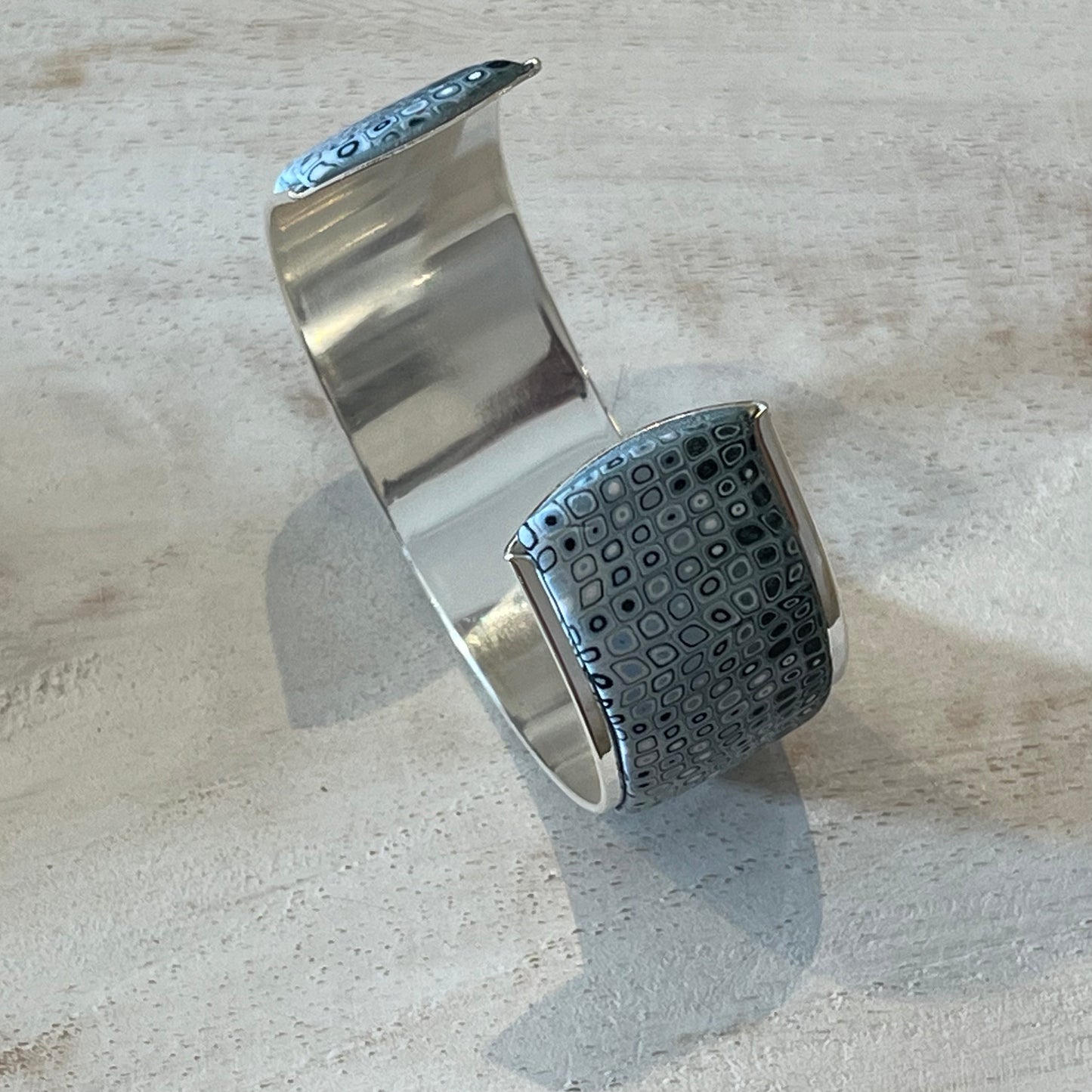 Handcrafted Sea Foam mosaic cuff by Stephanie Fraselle, featuring layered polymer clay canes in ocean-inspired patterns with sterling silver galvanized brass finish, adjustable fit, and hypoallergenic materials.