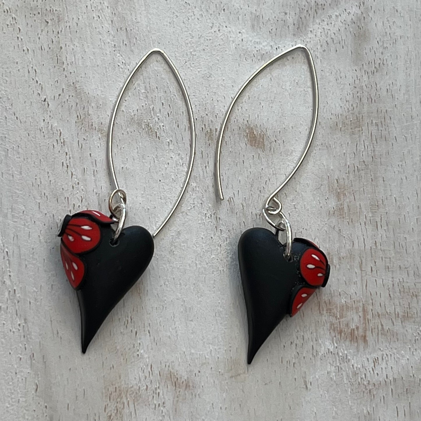 Handcrafted black heart-shaped earrings with red flower detail by Lanzarote artisan Stephanie Fraselle, paired with matching pendant (sold separately)