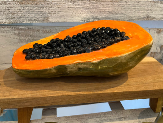 Hyperreal ceramic sculpture of halved papaya with glistening seeds in lifelike detail