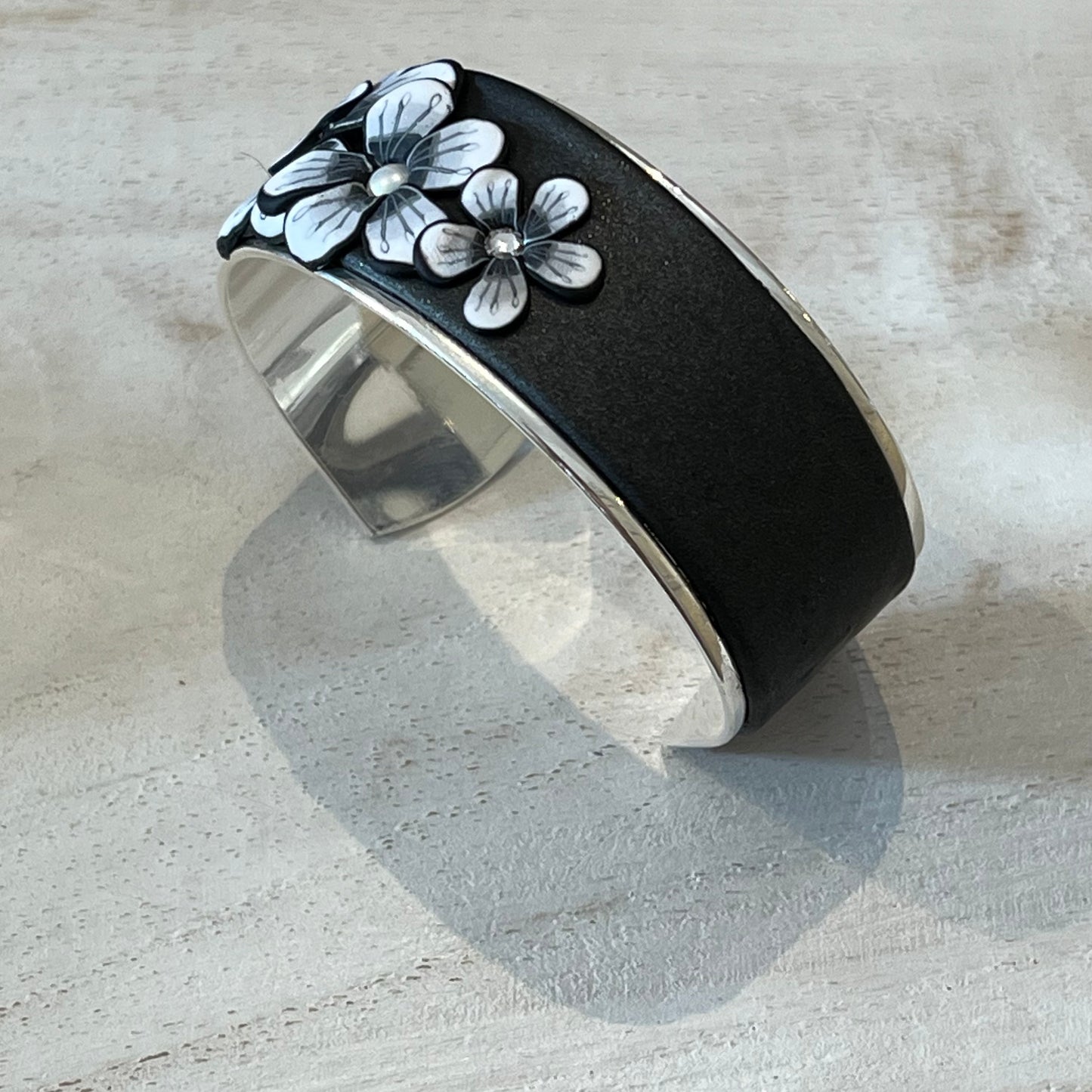 Moonlit Shimmer Blossom Cuff by Stephanie Fraselle featuring polymer clay florals and Swarovski crystals, handcrafted in Lanzarote