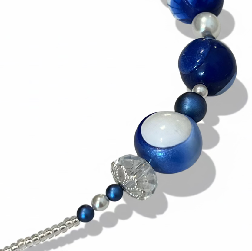 Seven-bead necklace from Stephanie Fraselle’s Marégraphie collection, featuring individually hand-sculpted polymer clay beads in sapphire, ultramarine, navy, white,accented with Swarovski crystals, pearls, Bohemian glass seed beads, and a 925 sterling silver heart toggle clasp, 51–52 cm length.