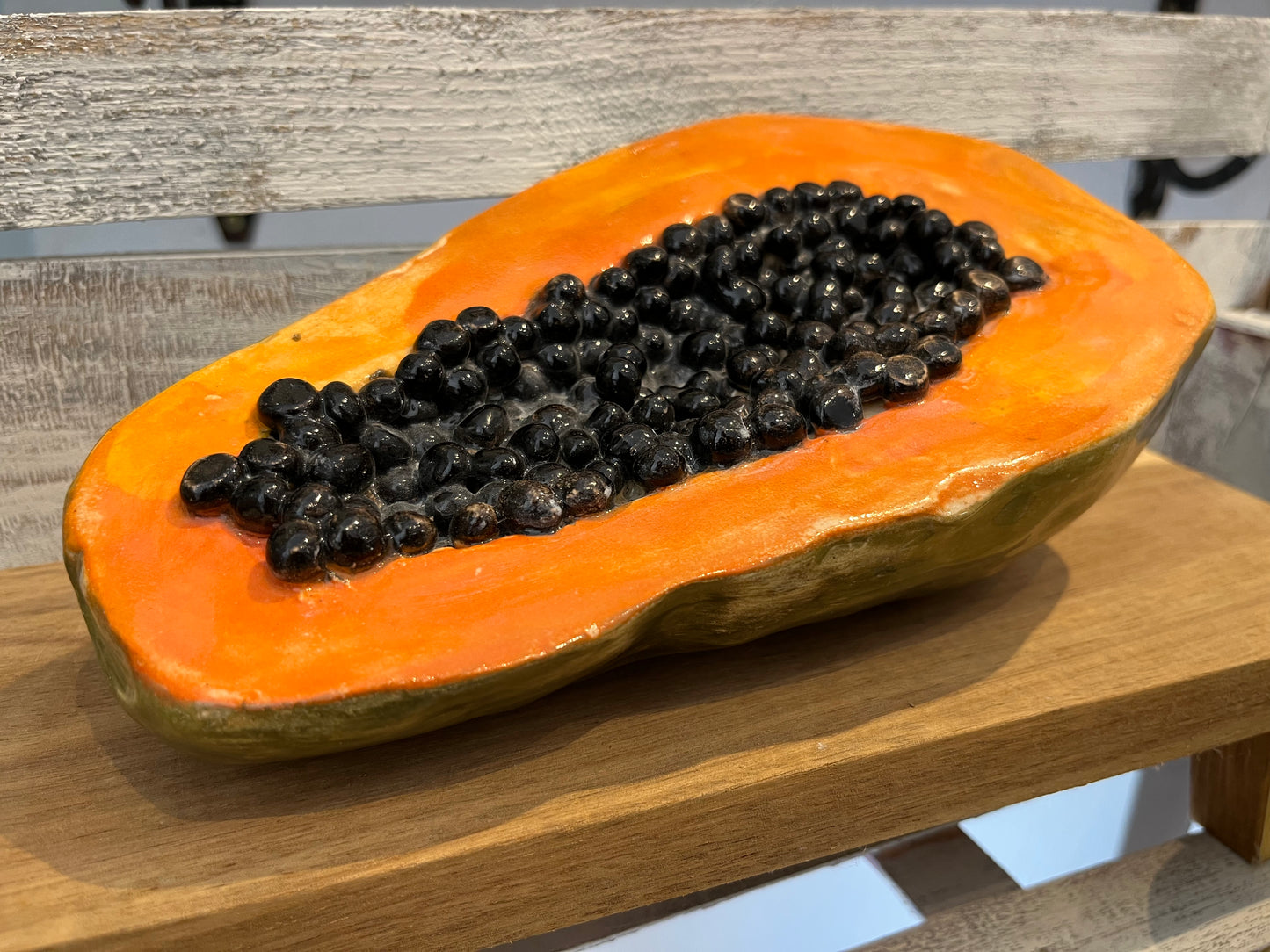 Hyperreal ceramic sculpture of halved papaya with glistening seeds in lifelike detail