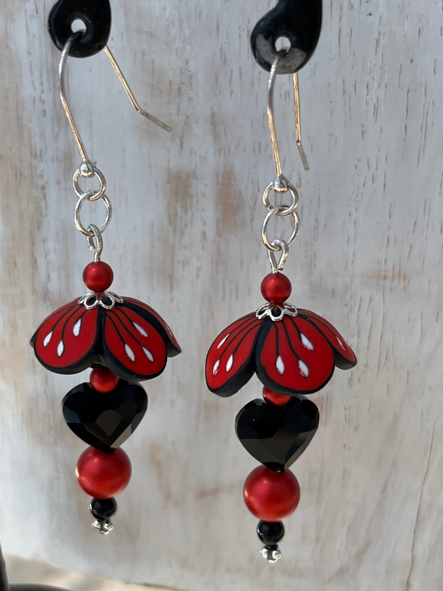 Close-up of Stephanie Fraselle’s Magic Moments Blossom Earrings – handcrafted red, white, and black polymer clay flowers with Swarovski crystal and pearl accents on sterling silver stems