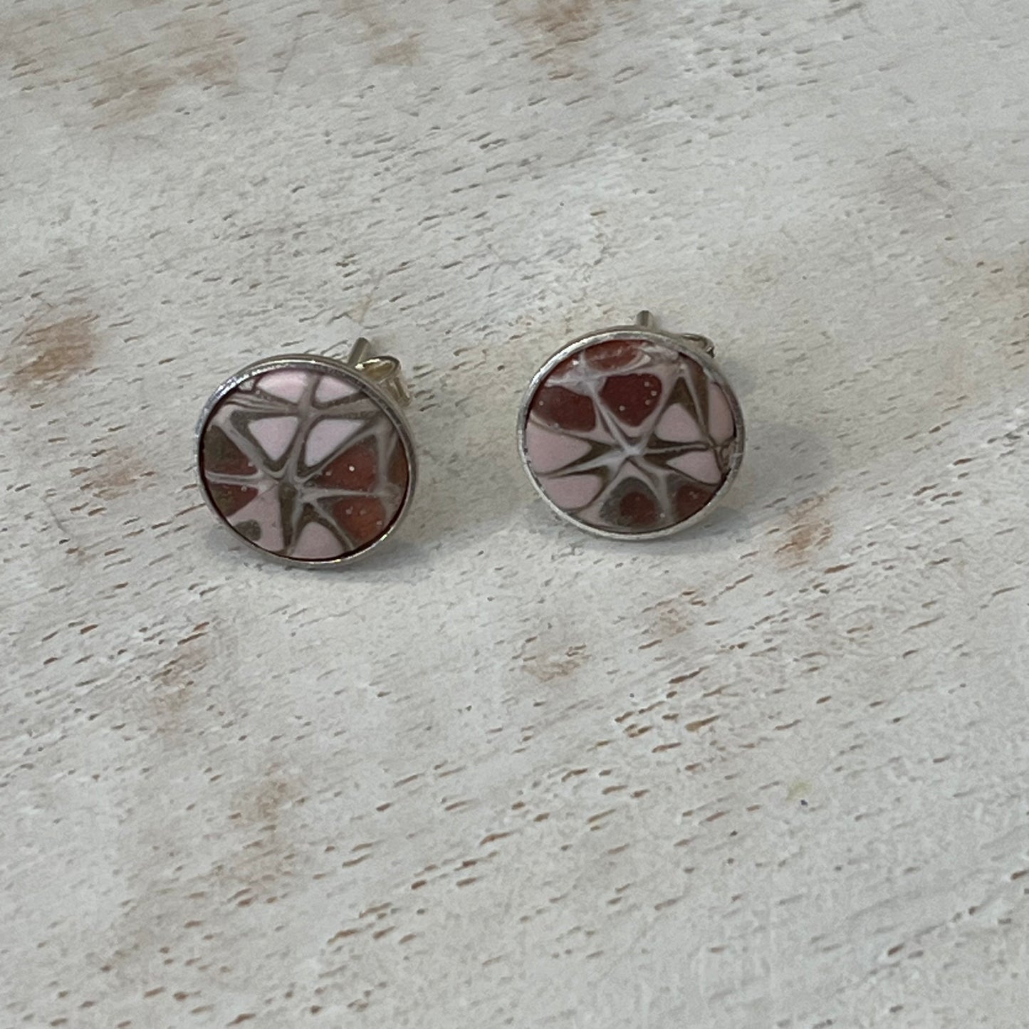 Close-up of mosaic stud earrings handcrafted by Stephanie Fraselle with pale pink, blush, gold, pearl tones and sterling silver settings.