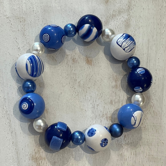 Handcrafted nine-bead bracelet from Stephanie Fraselle’s Marégraphie collection, featuring individually sculpted polymer clay beads in ocean blues and whites, accented with Swarovski crystals and pearls, strung on clear elastic cord, 20 cm length, 15 mm beads, lead-, cadmium-, and nickel-free.