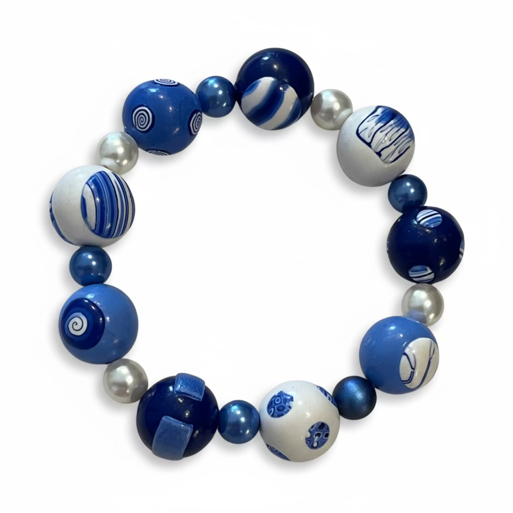Handcrafted nine-bead bracelet from Stephanie Fraselle’s Marégraphie collection, featuring individually sculpted polymer clay beads in ocean blues and whites, accented with Swarovski crystals and pearls, strung on clear elastic cord, 20 cm length, 15 mm beads, lead-, cadmium-, and nickel-free.
