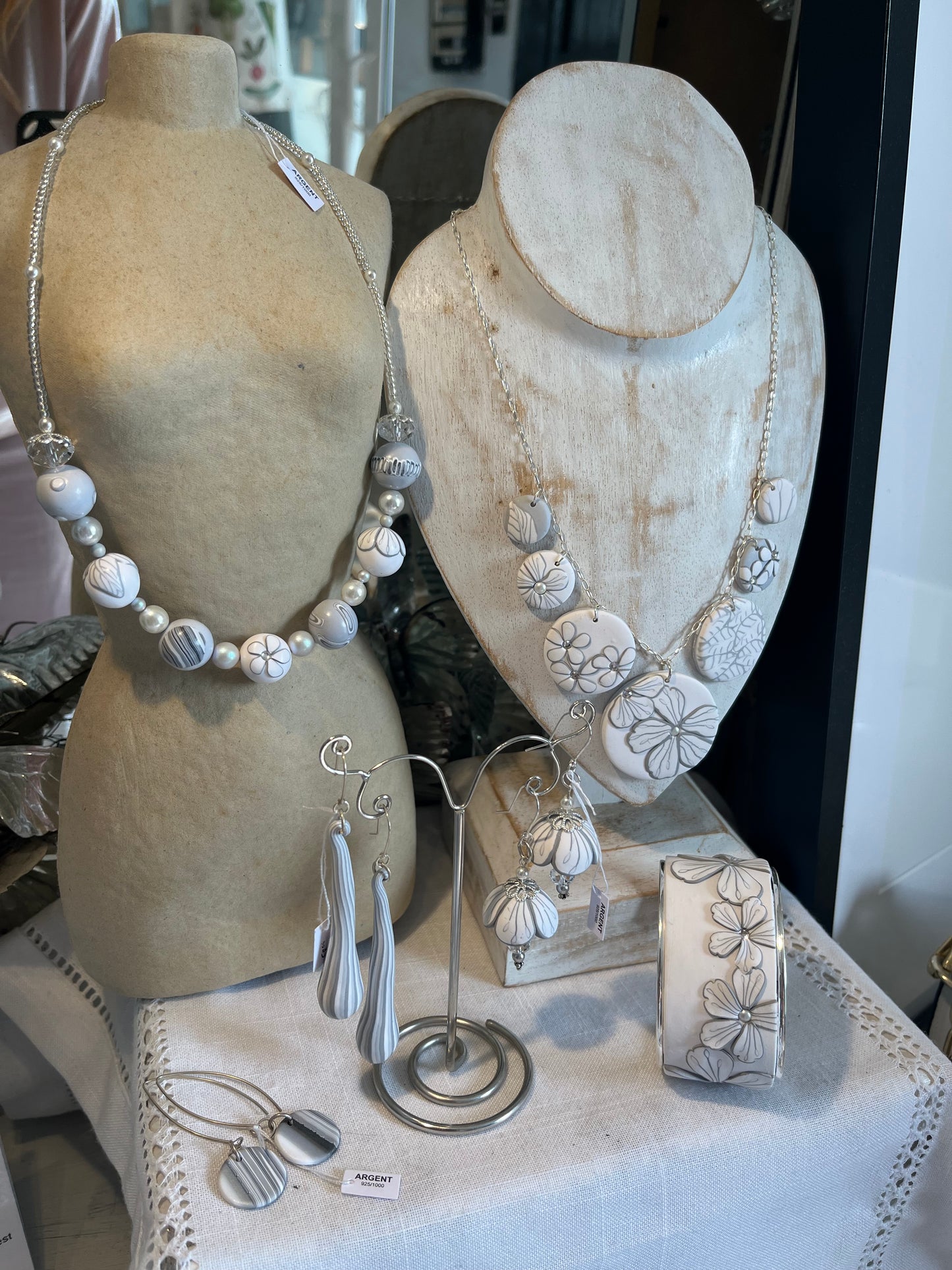 The Seven necklace from the White Blossom Collection by Stephanie Fraselle featuring seven handcrafted polymer clay medallions with botanical motifs, Swarovski crystals, and pearls on a sterling silver chain.