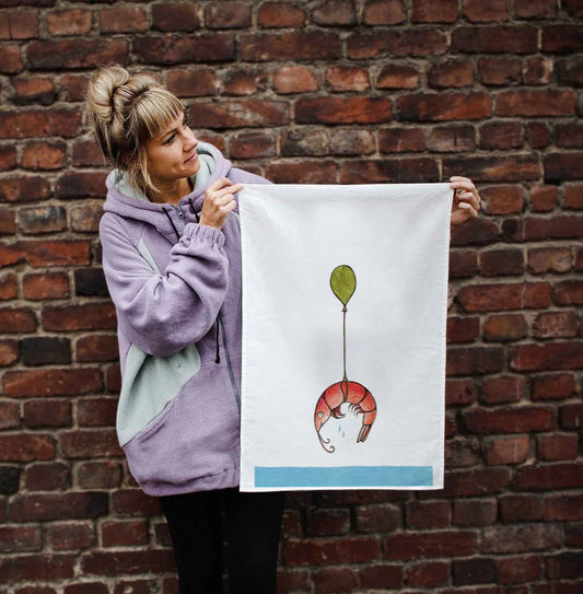 Artistic linen tea towel depicting a shrimp floating across the ocean by balloon