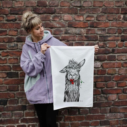 Linen tea towel featuring Steven the Llama holding a chewed red rose in his mouth