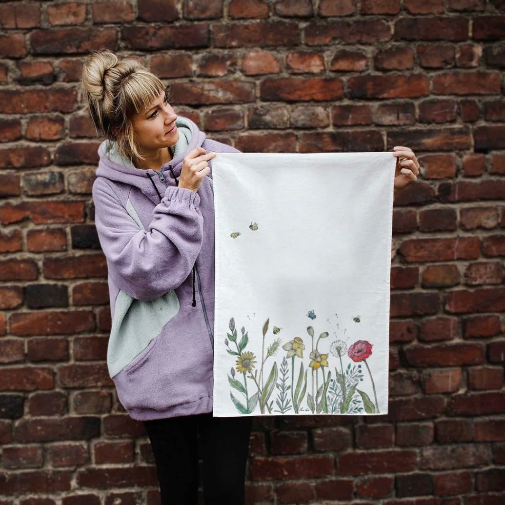 Colourful illustration of a wildflower meadow with bees printed on a linen tea towel