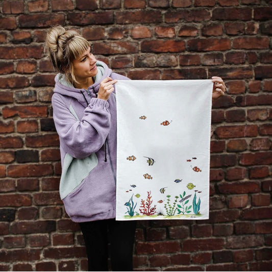 Colourful illustration of a coral reef with fishes swimming happily on a linen tea towel