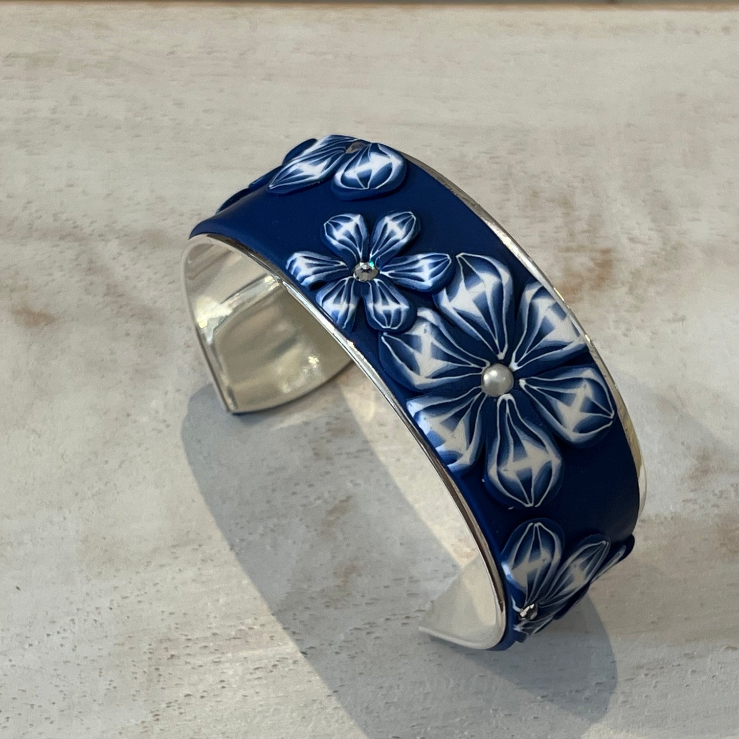 Midnight Bloom Cuff by Stephanie Fraselle with navy and white floral polymer clay, Swarovski pearls, and sterling silver finish