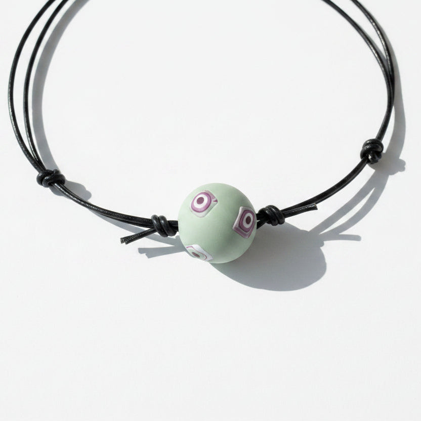 Necklace with a green bead on a light wooden surface