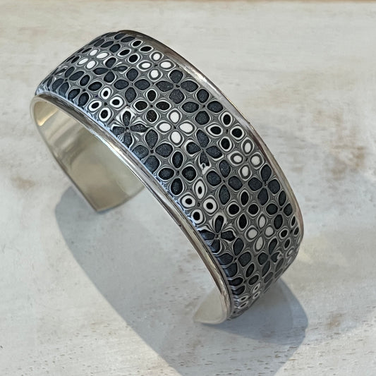Moonlit Shimmer Cuff by Stephanie Fraselle featuring a hand-placed mosaic of polymer clay tiles in grey, white, and silver tones, set in sterling silver-coated brass.