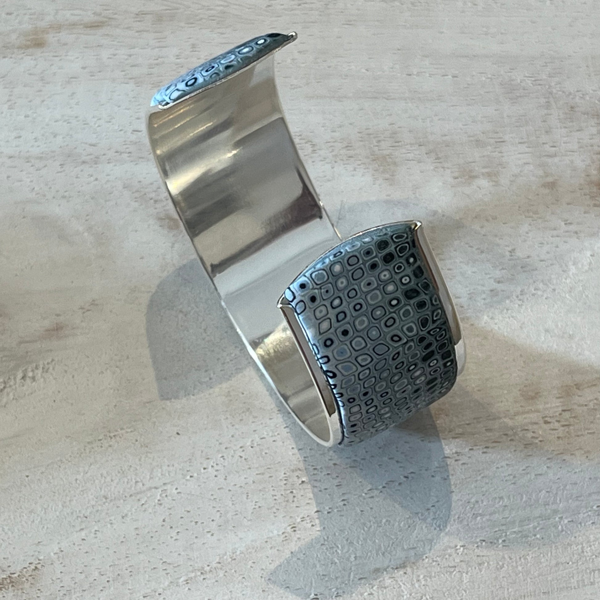 Handcrafted Sea Foam mosaic cuff by Stephanie Fraselle, featuring layered polymer clay canes in ocean-inspired patterns with sterling silver galvanized brass finish, adjustable fit, and hypoallergenic materials.