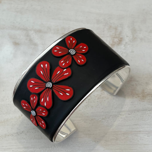 Unique handmade cuff by Lanzarote artisan Stephanie Fraselle featuring bold red and white floral accents on matte black polymer clay with silver-plated brass base