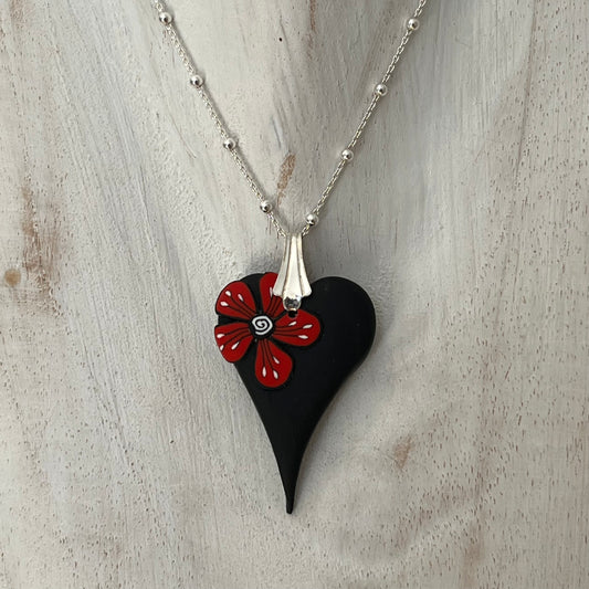 Handmade curved black heart pendant with red flower accent on sterling silver chain by Lanzarote artisan Stephanie Fraselle