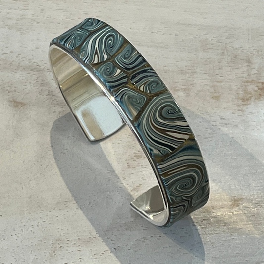 Handcrafted Nocturne cuff by Stephanie Fraselle in sterling silver-coated brass with gold, pearlescent, and petrol blue tones