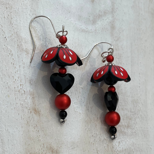 Close-up of Stephanie Fraselle’s Magic Moments Blossom Earrings – handcrafted red, white, and black polymer clay flowers with Swarovski crystal and pearl accents on sterling silver stems