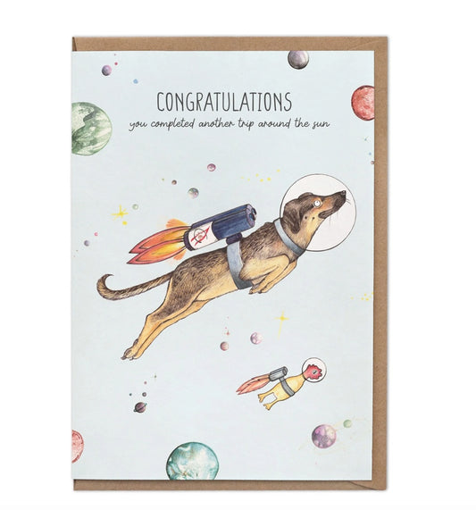 Bamboo greeting card featuring Lottie the dog floating in space with the message “Congratulations, you have completed another trip around the sun”